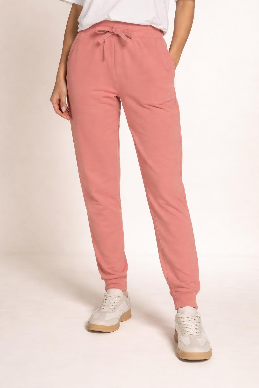 Close-up of the model's lower body wearing Tovolea Embroidered Dusty Rose Fleece Sweatpants