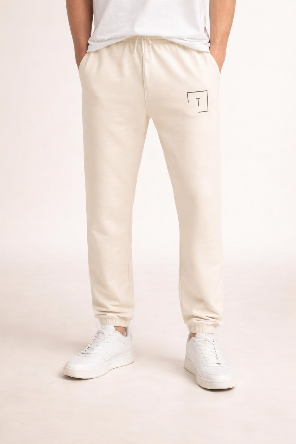 Close-up of the model's lower body wearing Tovolea Gents Ivory Embroidered Fleece Sweatpants