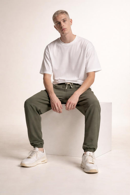 Model sitting while wearing Tovolea Gents Grey Embroidered Fleece Sweatpants